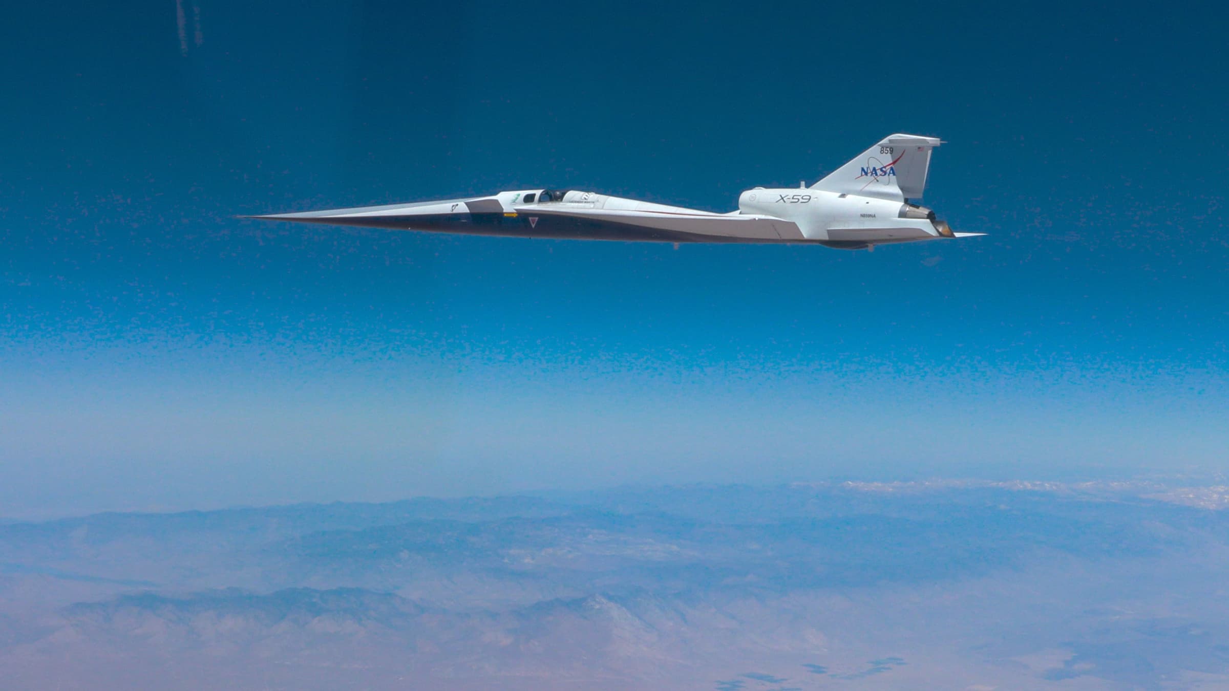 NASA's white X-59 research aircraft flying in side profile above California during its first supersonic flight.